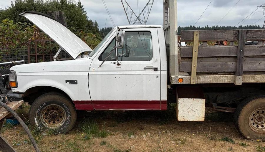 White Ford flatbed truck with the hood up